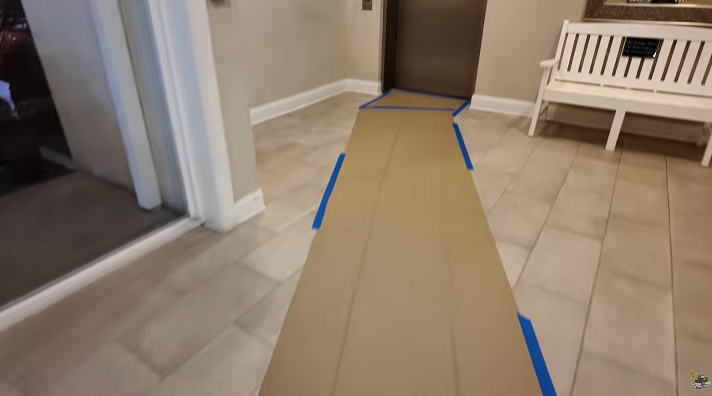 Taped floor protection path across a condo building lobby leading to the elevator