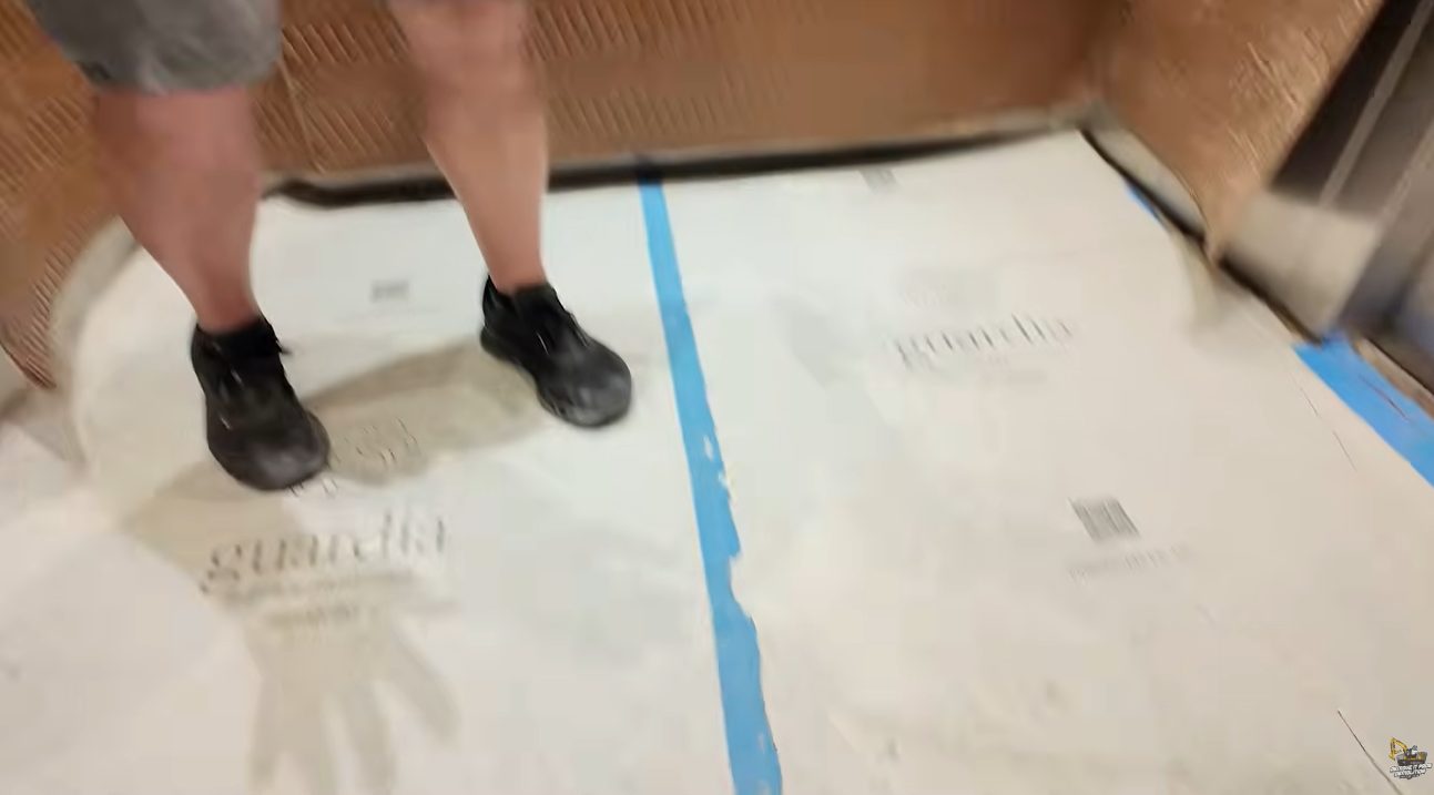Elevator floor covered with protective board and taped seams before demolition debris is moved